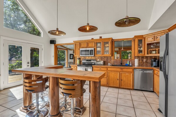 Una cocina moderna con gabinetes de madera, electrodomésticos de acero inoxidable y una amplia mesa de comedor con taburetes de bar.