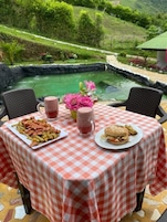 Una mesa con mantel a cuadros, dos sillas, un plato de comida, una bebida y un arreglo floral.