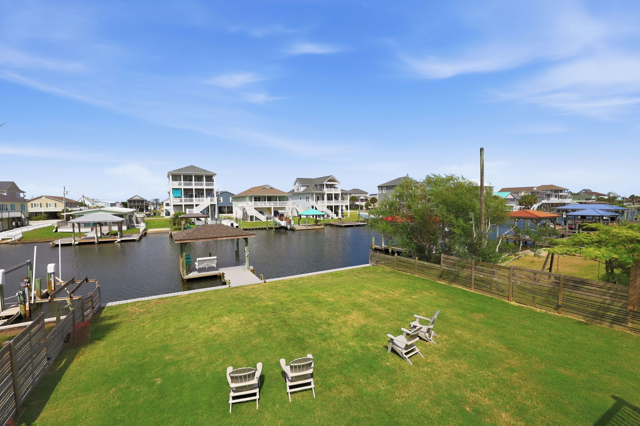 A residential area with a dock, a grassy lawn, and houses.