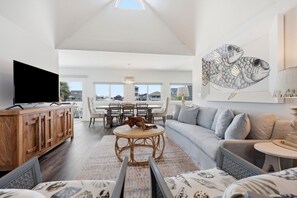 Ein modernes Wohnzimmer mit Fernseher, Sofa, Esstisch und Kunstwerken.
