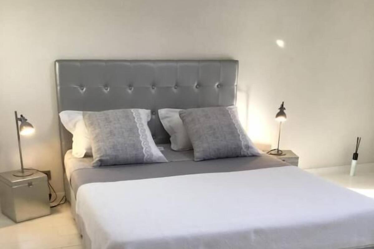 A modern bedroom with a large bed, two bedside tables, and two wall-mounted lamps.