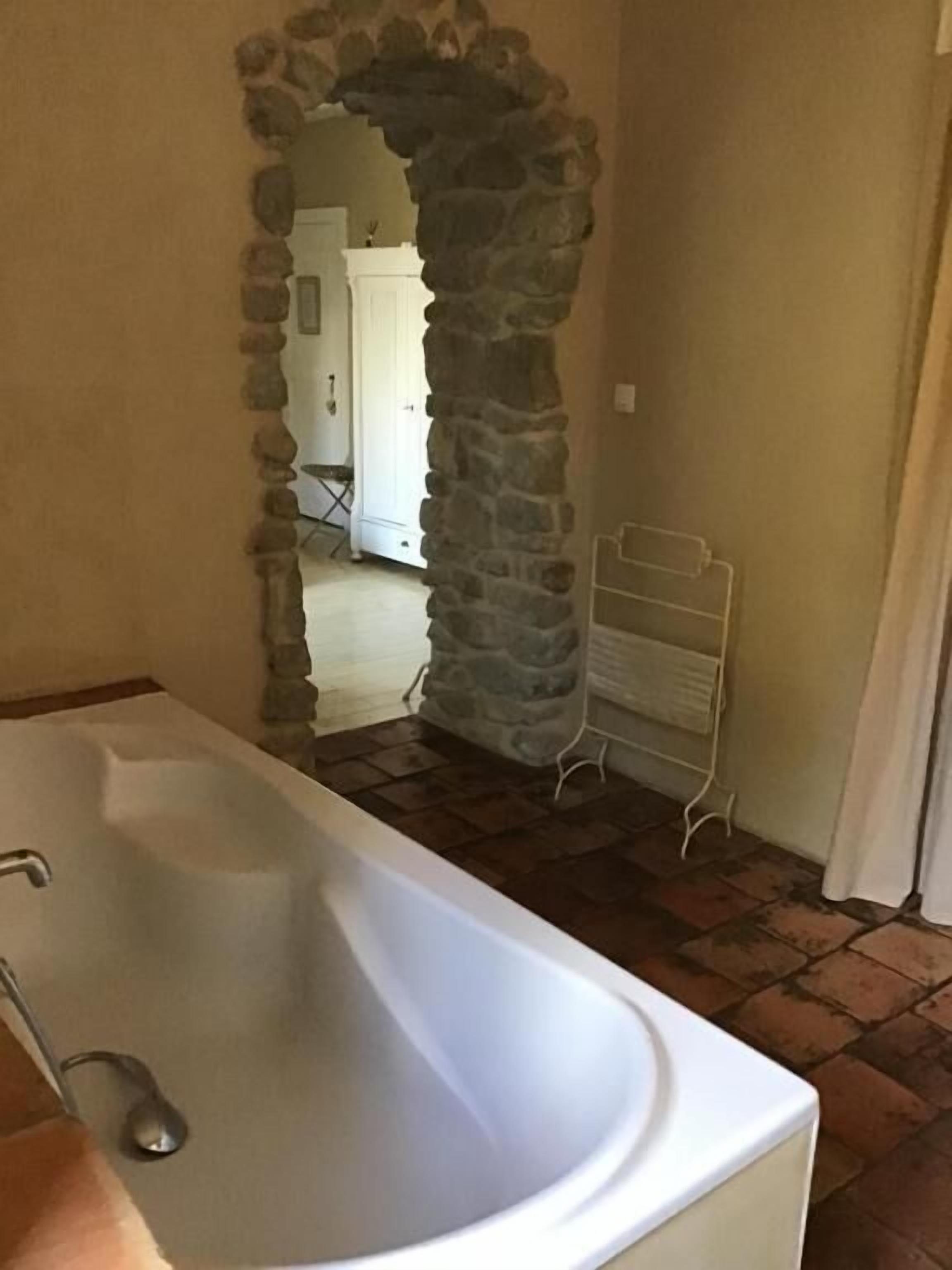 A bathroom with a stone archway leading to a hallway.