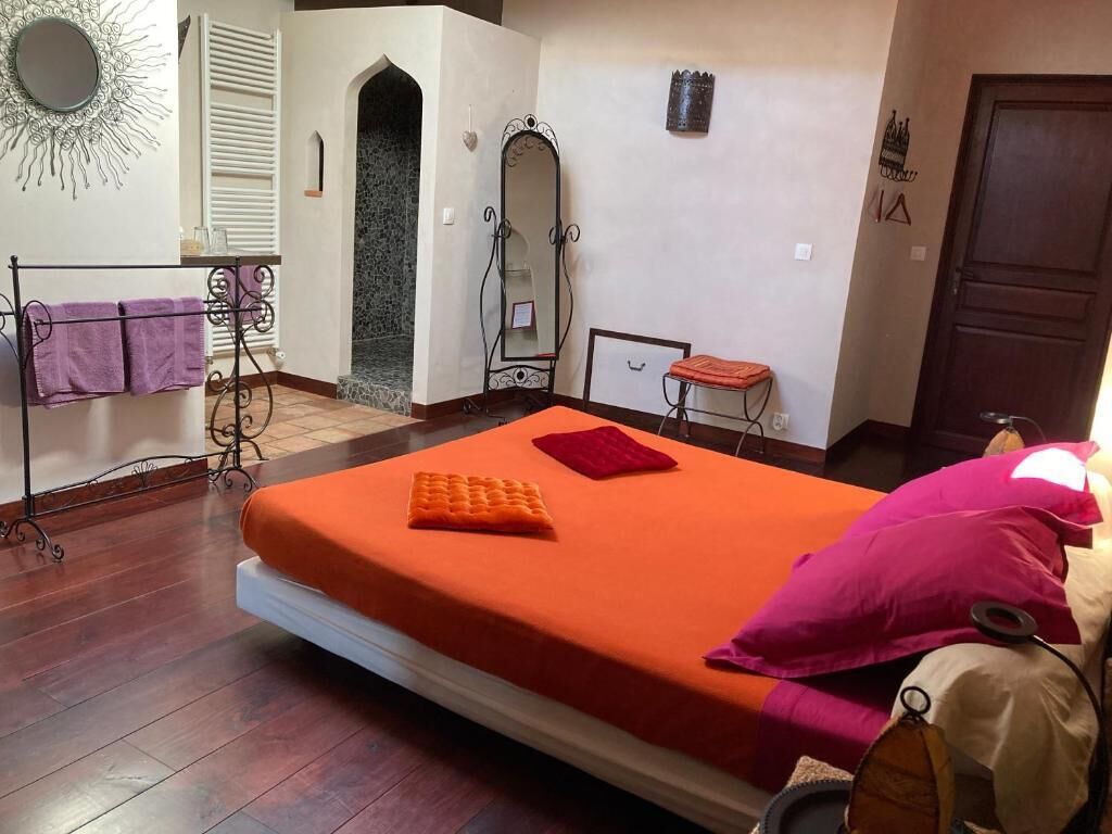 Ein Schlafzimmer mit Bett, Schminktisch mit Spiegel, kleinem Tisch und einer Tür.