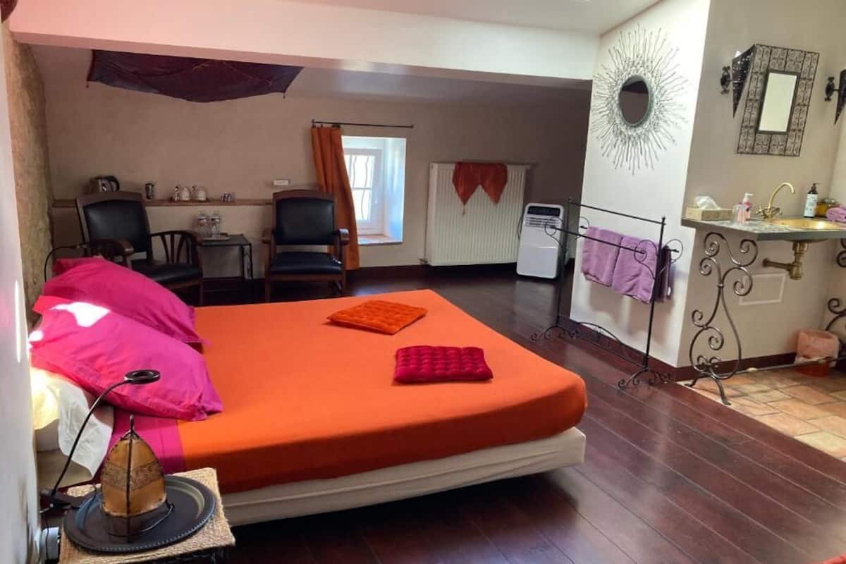 A room with a bed, a desk, a chair, a radiator, and a bathroom area.