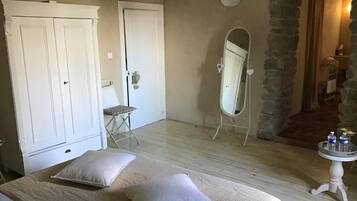 Ein Schlafzimmer mit einem Bett, zwei Kissen, einem Kleiderschrank, einem Spiegel und einem kleinen Tisch mit Gegenständen darauf.