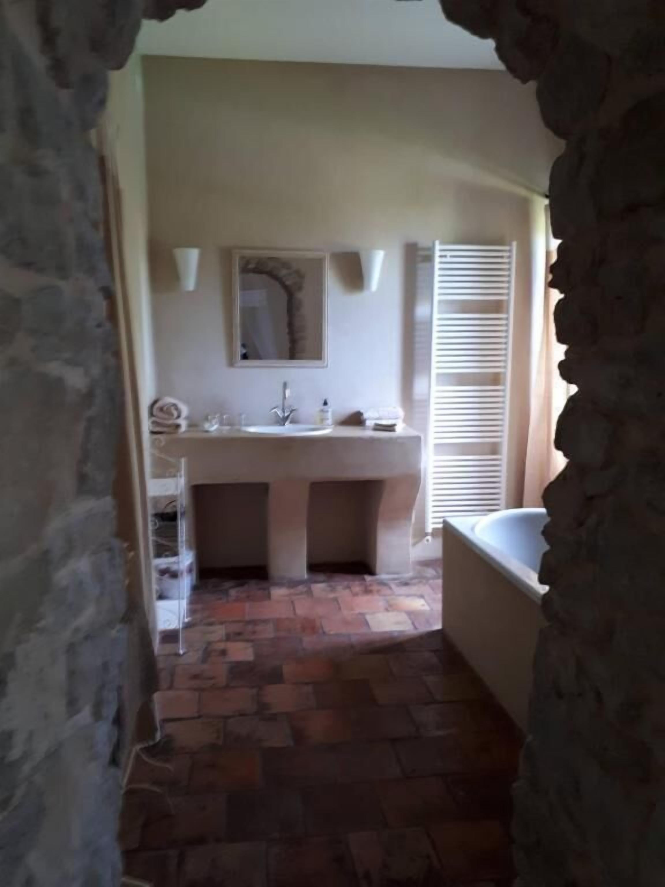 Un baño con suelo de piedra, un lavabo con espejo y una bañera.