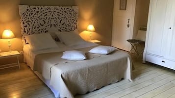 A neatly made bed with a decorative headboard, two bedside lamps, and a white wardrobe.