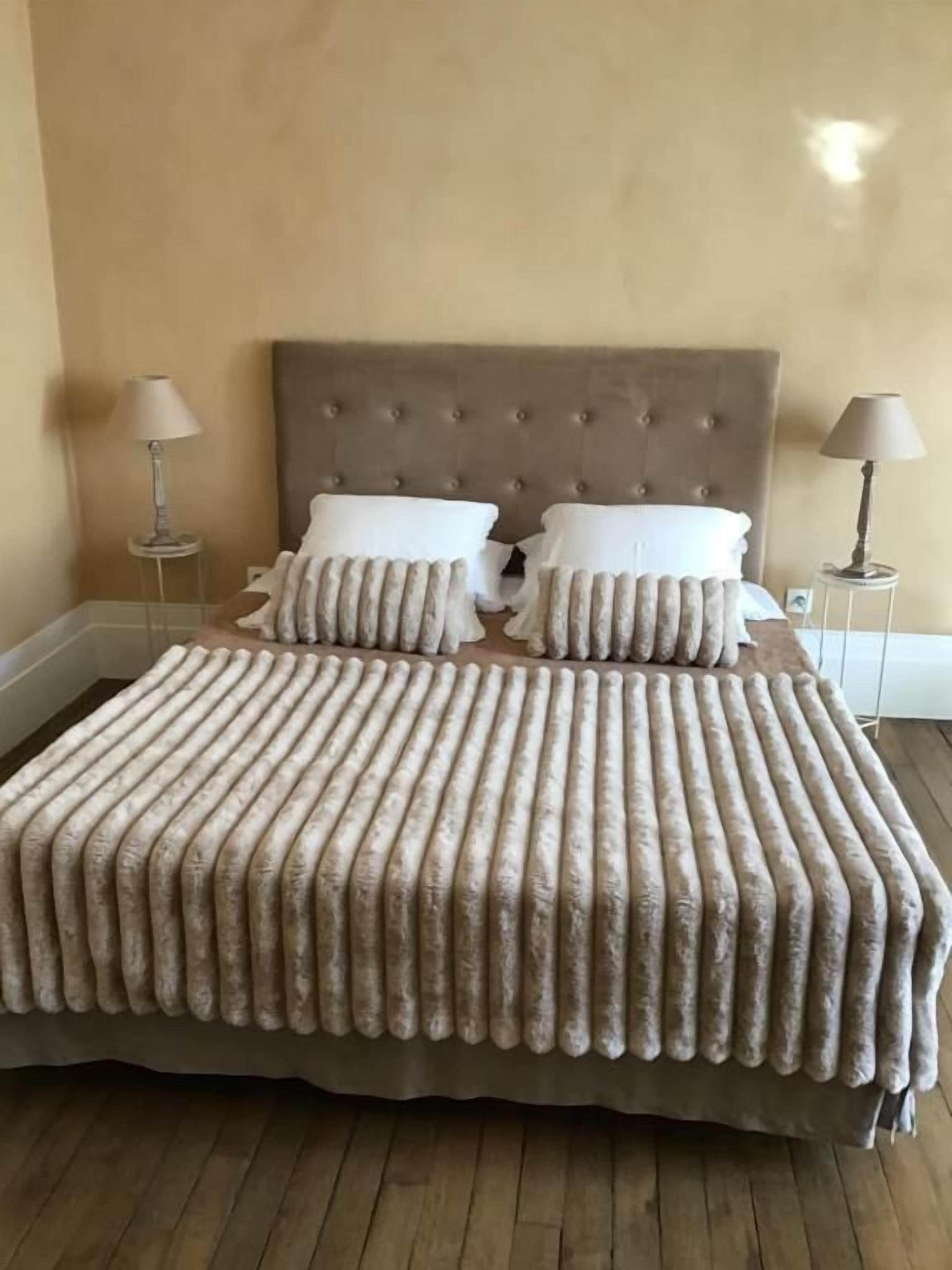 Una cama con cabecera capitonada, dos mesitas de noche con lámparas y una colcha estampada.