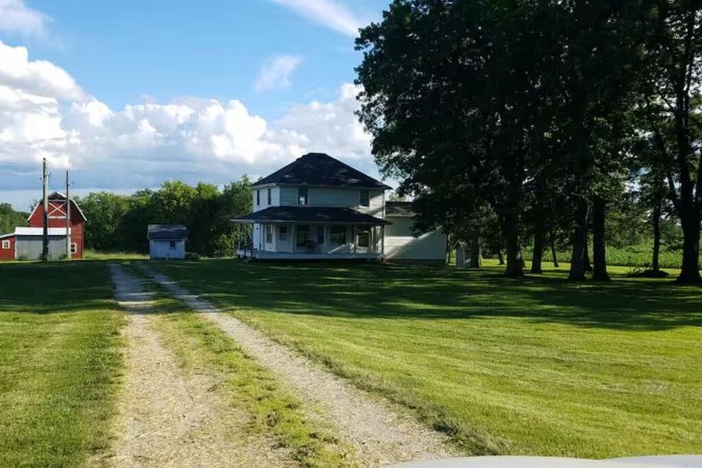 A rural property with a large house, a barn, and a well-maintained lawn.