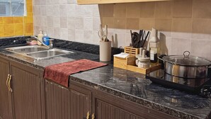 Une cuisine dotée d’un plan de travail en granit, de meubles en bois et d’une fenêtre avec des stores.