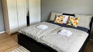 Un dormitorio con cama, armario y mesita de noche.