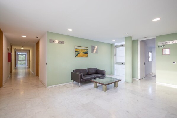 Un hall d’entrée moderne avec un canapé et une table basse, un tableau au mur et des panneaux d’orientation.