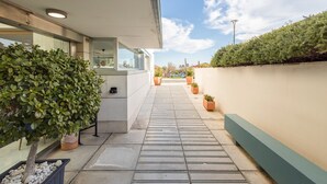 A modern building with a covered outdoor area, potted plants, and a clear sky. - GuestReady - Domocenter studio with garage (Bormujos)