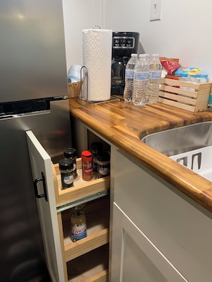 Une cuisine équipée d’un réfrigérateur en acier inoxydable, d’un plan de travail en bois, d’une machine à café et de divers ustensiles de cuisine.