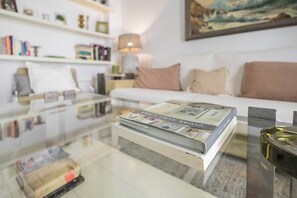 Ein modernes Wohnzimmer mit einem Glastisch, einem weißen Sofa und einem Bücherregal.