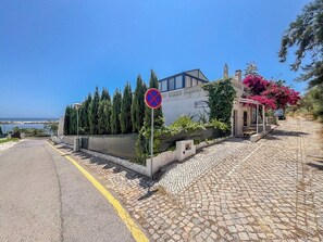 Eine Küstenstraße mit einem Verbotsschild für Parkplätze, ein Gebäude mit blauem Dach und Blick auf das Meer.