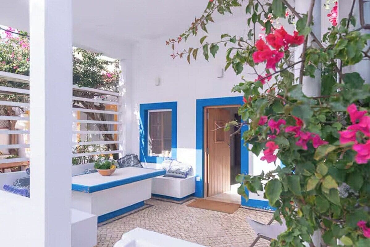 Una stanza in bianco e blu con un letto, una finestra e una porta.