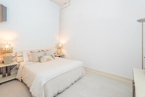 Een minimalistische slaapkamer met een bed, nachtkastjes en een lamp.