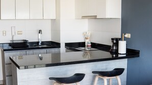Eine moderne Küche mit schwarzer Arbeitsplatte, weißen Schränken und zwei schwarzen Barhocker.