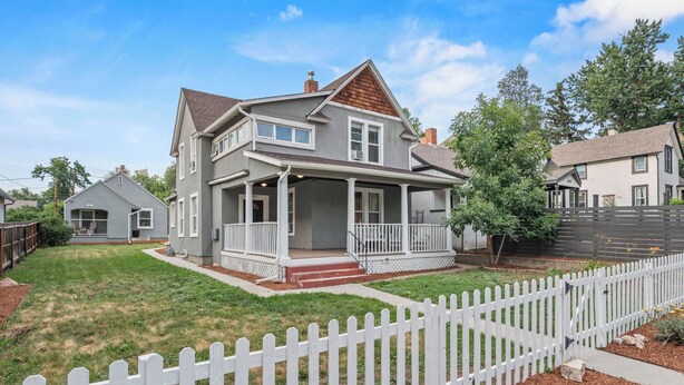 A two-story house with a porch, a white picket fence, and a well-maintained lawn. - Spacious Downtown Retreat w/ Private Yard & Mountain Views (Colorado Springs)