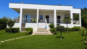 Una casa moderna de dos pisos con un porche cubierto, una escalera de piedra y un césped bien cuidado.