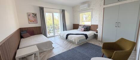 Une chambre moderne avec deux lits, une petite table, une chaise et une armoire.