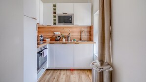 Eine kleine Küche mit weißen Schränken, einer Mikrowelle, einem Spülbecken und Holz Arbeitsplatten.