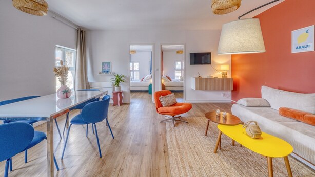 Ein modernes Wohnzimmer mit Essbereich, einer Couch, einem Couchtisch und einem an der Wand befestigten Fernseher.