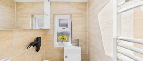 A modern bathroom with skylights, a toilet, a sink, and a towel rack.