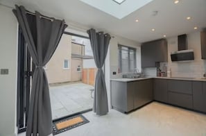 A modern kitchen with grey cabinets, a built-in oven, and a window overlooking the backyard.
