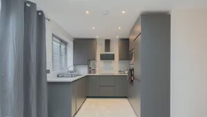 Una cocina moderna con armarios grises, una isla central y un horno empotrado.