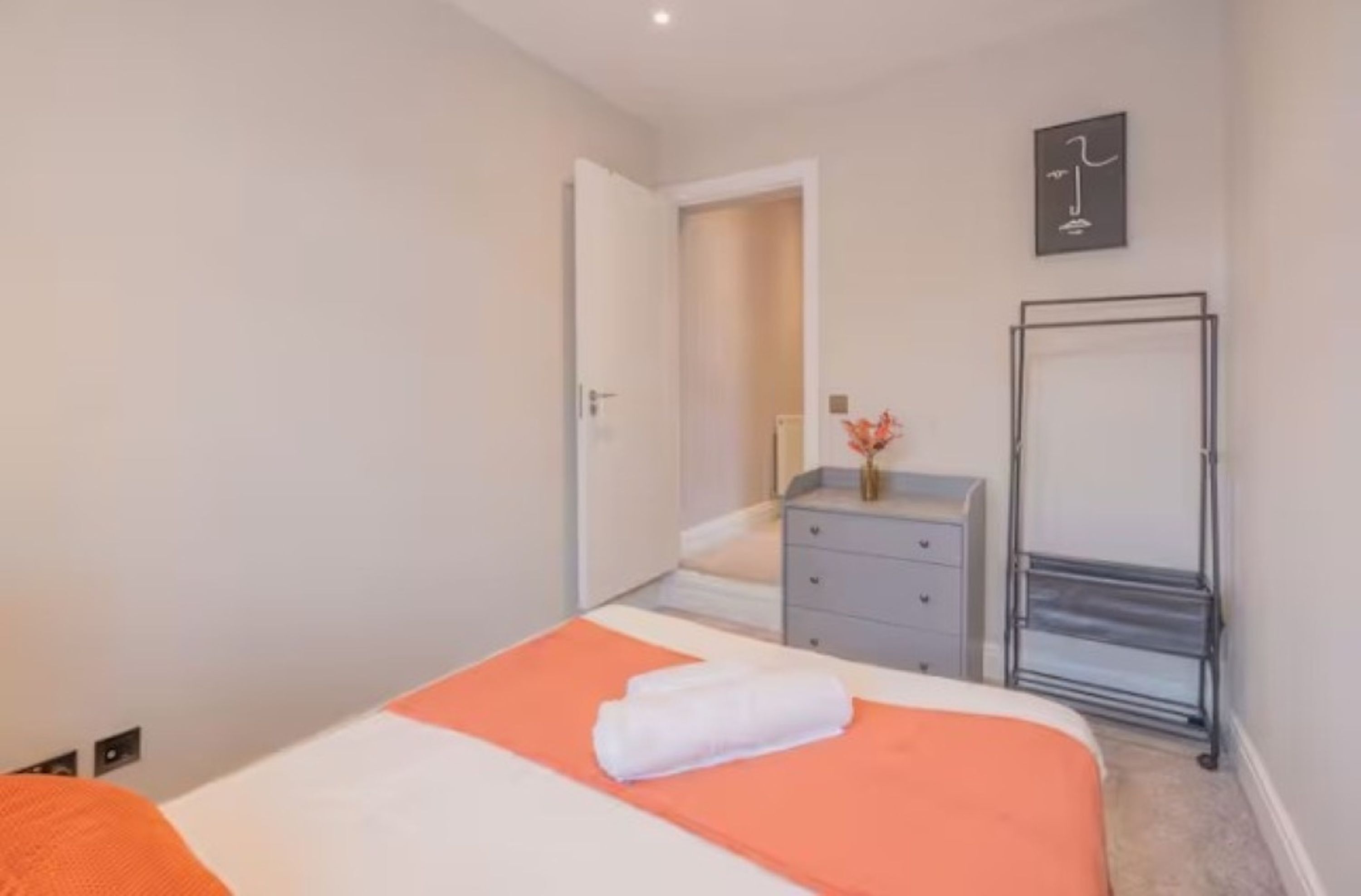 Una habitación de hotel con cama, cómoda, espejo y puerta que da a otra habitación.