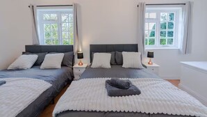 A double room with two beds, each with a headboard, bedside tables, and lamps. There are windows with curtains, and the room has a neutral color scheme. - 3BR Putney Home London Sleeps 8 Winter Deal (London)