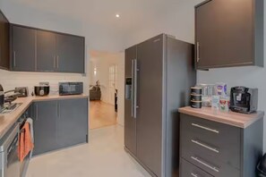A modern kitchen with grey cabinets, a built-in microwave, a coffee machine, and a refrigerator. - 3BR Putney Home London Sleeps 8 Winter Deal (London)