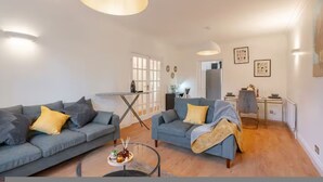 A modern living room with two grey sofas, a coffee table, and a dining area with a table and chairs. - 3BR Putney Home London Sleeps 8 Winter Deal (London)