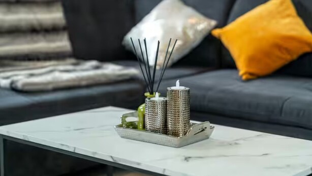 Un salon moderne avec un canapé gris, un plaid blanc et un coussin jaune.