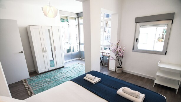 Un dormitorio moderno con una cama grande, un armario, un escritorio y una ventana con vistas al exterior.