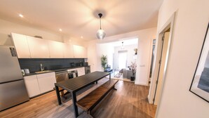 Una cocina moderna con un banco de madera, armarios blancos y encimera negra.