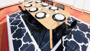 Terraza en la azotea con una mesa preparada para cuatro personas, rodeada de sillas y protegida por un paraguas rojo.