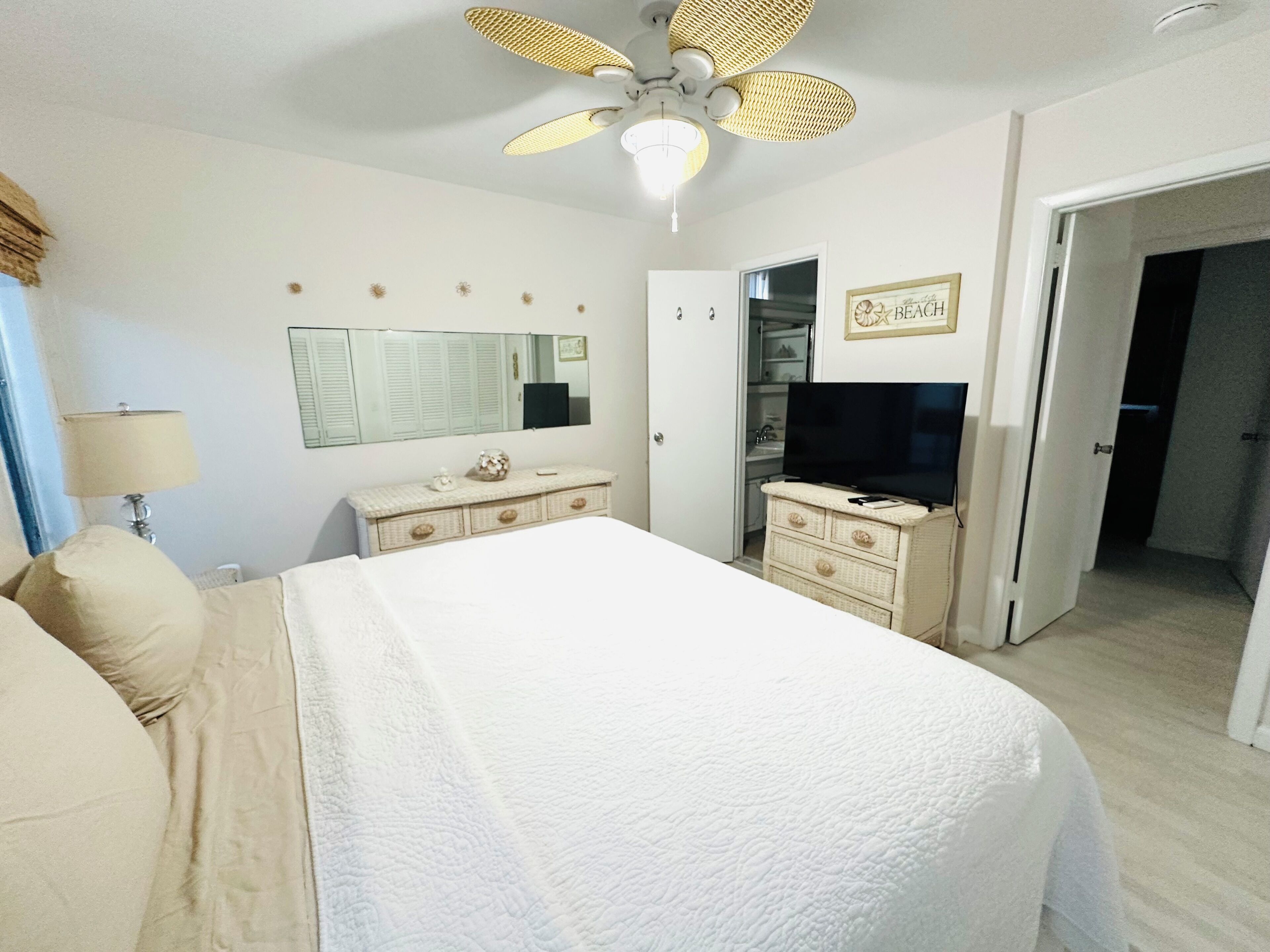 Ein Schlafzimmer mit Bett, Kommode, Fernseher und Deckenventilator.