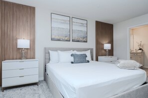 Ein modernes Hotelzimmer mit einem großen Bett, zwei Nachttischen mit Lampen, einer Wand aus Holzpaneelen und zwei abstrakten Gemälden.