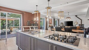Una cocina moderna con una isla central, electrodomésticos de acero inoxidable e iluminación colgante.