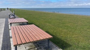 Un paseo marítimo con bancos y un camino pavimentado que lleva al mar.
