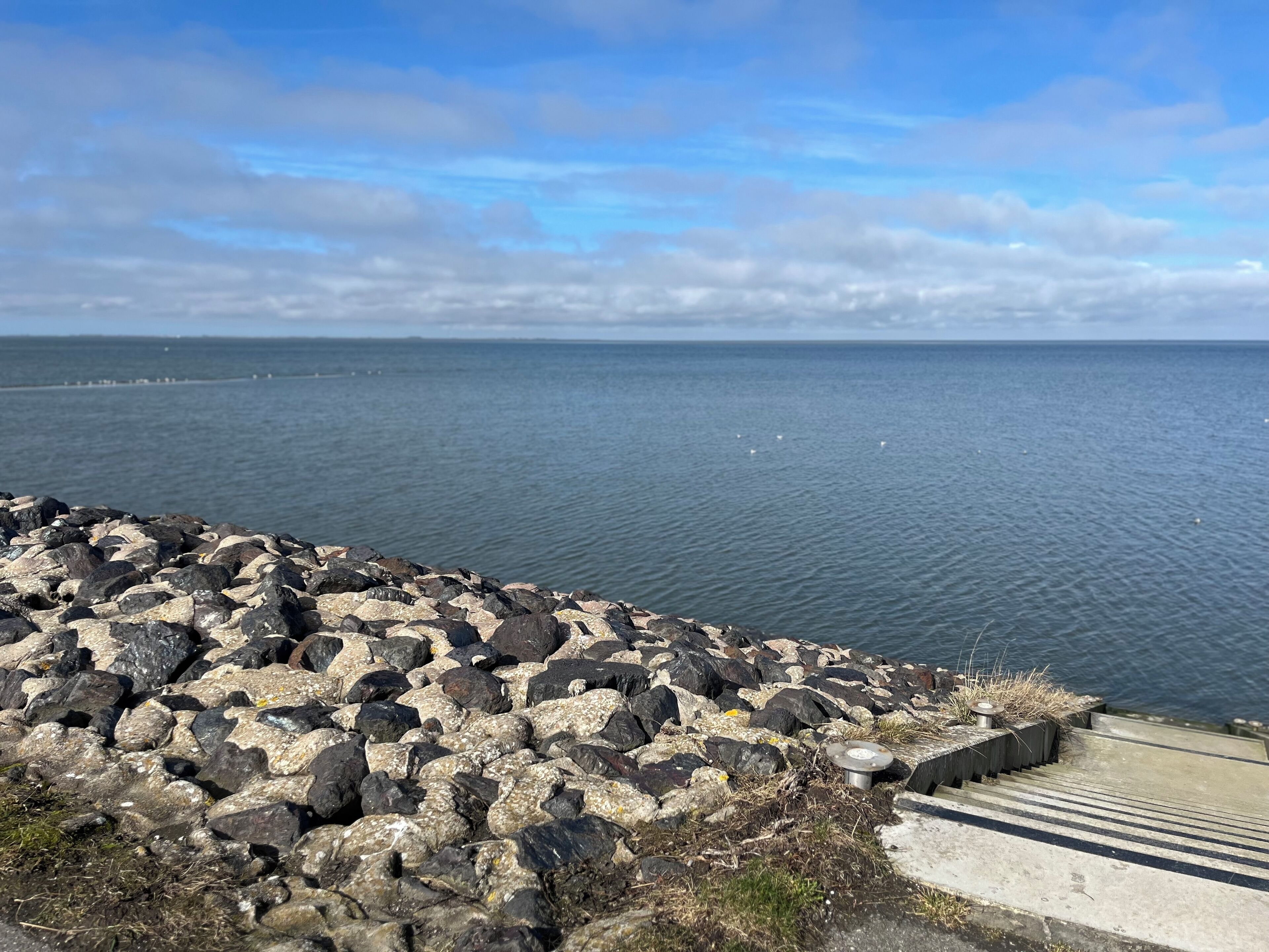 A rocky shoreline with a view of the sea and a clear sky.