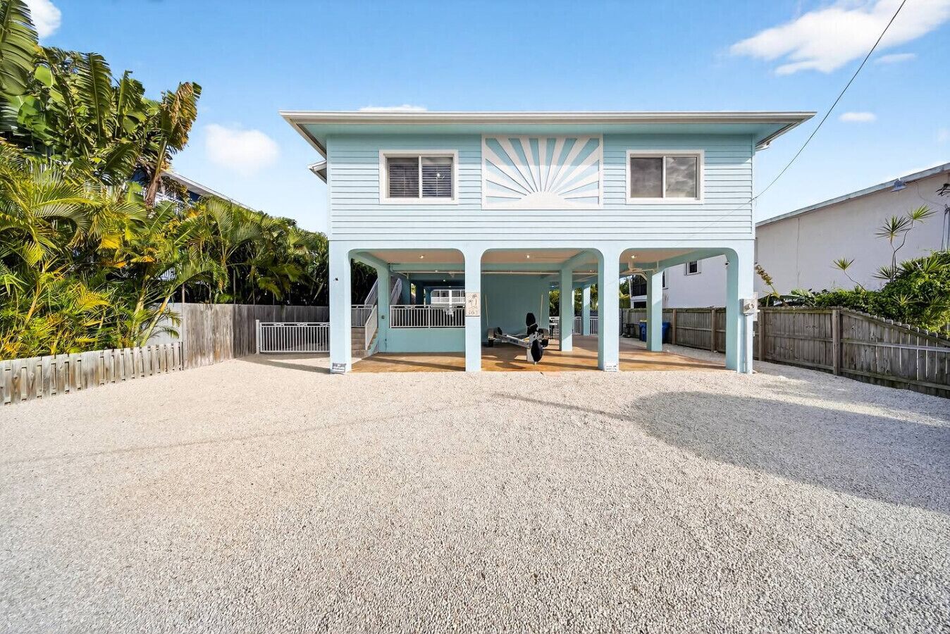 A light blue house with a covered porch and a gravel driveway.