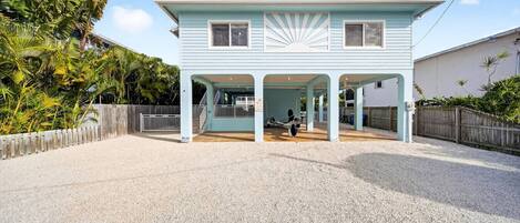 A light blue house with a covered porch and a gravel driveway.