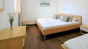 Ein sauberes, modernes Schlafzimmer mit einem Holzbett, einem Nachttisch und einem Fenster mit Vorhängen.