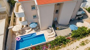 Ein mehrstöckiges Gebäude mit Schwimmbad, Außenbereich und einem roten Ziegeldach.