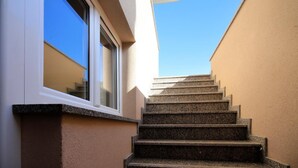 Steinerne Stufen führen zu einem Fenster mit weißem Rahmen an einer beigen Wand.