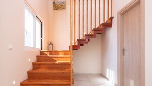 A wooden staircase leading to a door, with a window on the left and a painting on the wall. - Villa Ocean Pool in Planos (Zakynthos)
